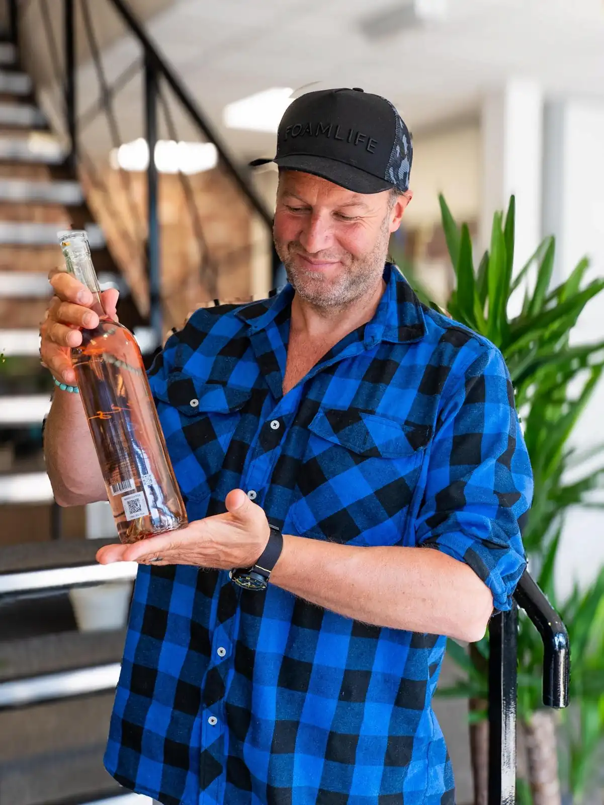 Photo of a main in a checked shirt holding up a drink bottle.